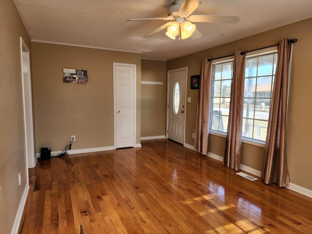 entrance foyer with hardwood / wood-style flooring, ceiling fan, crown molding, and a textured ceiling