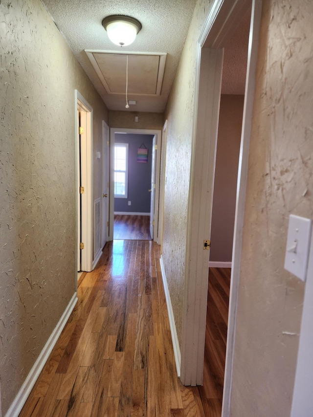 corridor with dark wood-type flooring and a textured ceiling