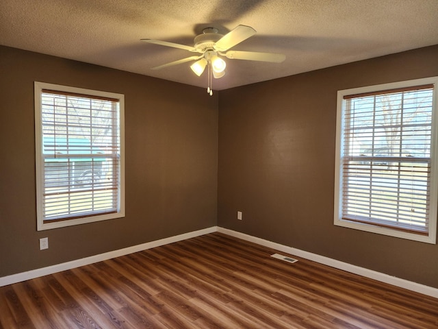 spare room featuring dark wood-type flooring, ceiling fan, and a textured ceiling