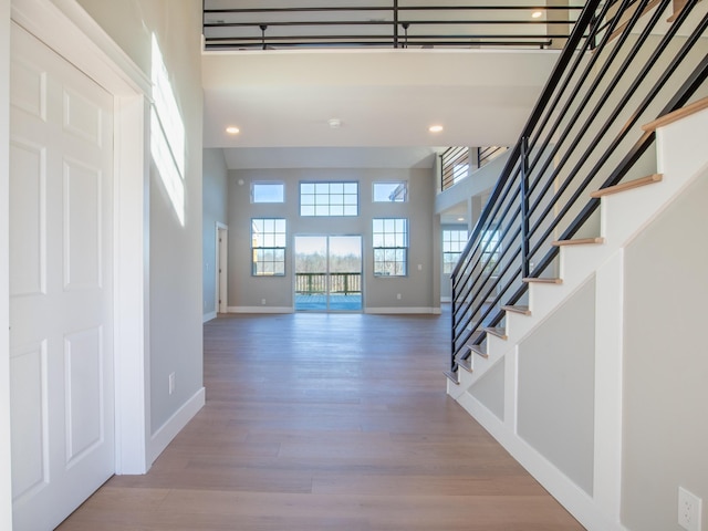 foyer entrance featuring a towering ceiling and light hardwood / wood-style floors