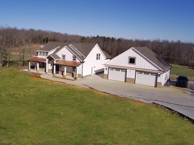 modern farmhouse featuring a porch, a garage, and a front lawn