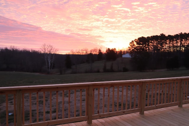 deck at dusk featuring a lawn