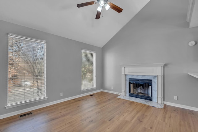 unfurnished living room featuring ceiling fan, high vaulted ceiling, a fireplace, and light wood-type flooring