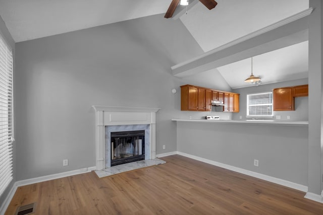 unfurnished living room featuring high vaulted ceiling, wood-type flooring, ceiling fan, a high end fireplace, and beam ceiling