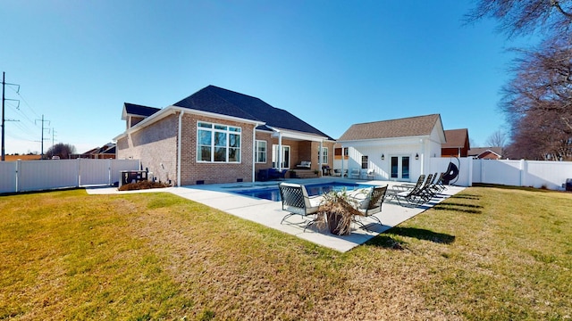 rear view of house with a fenced in pool, a yard, a patio area, and french doors