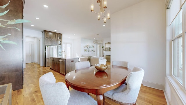 dining room featuring sink, a notable chandelier, and light wood-type flooring