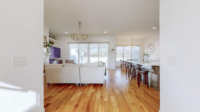 living room with light hardwood / wood-style floors and a notable chandelier