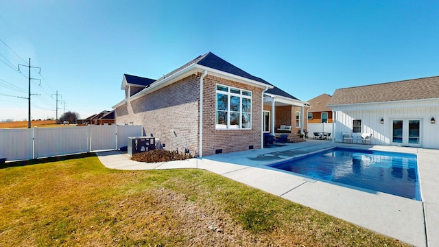 rear view of house featuring a fenced in pool, a yard, french doors, and a patio area