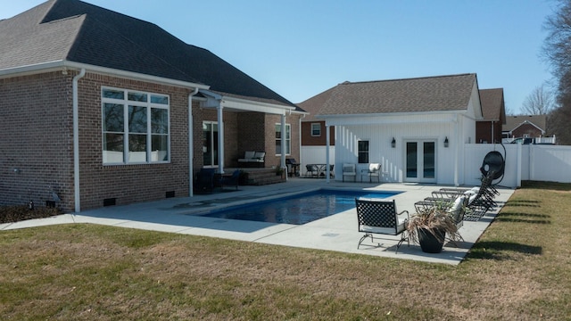 rear view of house with a fenced in pool, a patio, a yard, and french doors