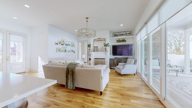 living room featuring french doors, an inviting chandelier, and light hardwood / wood-style flooring