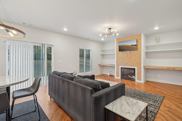 living room featuring a notable chandelier, light hardwood / wood-style floors, and a large fireplace