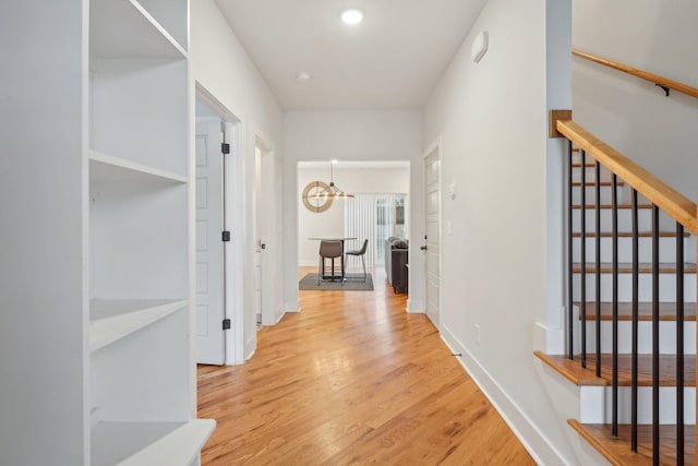 hall with a notable chandelier and light hardwood / wood-style floors