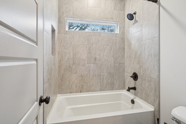 bathroom with tiled shower / bath combo and toilet