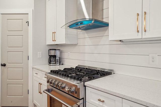 kitchen featuring gas range, white cabinetry, light stone counters, and exhaust hood