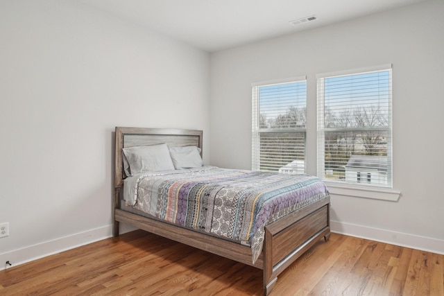 bedroom with multiple windows and light hardwood / wood-style flooring