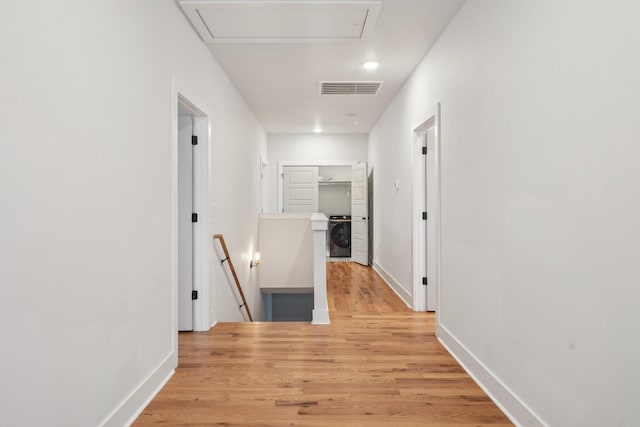 corridor with washer / clothes dryer and light wood-type flooring