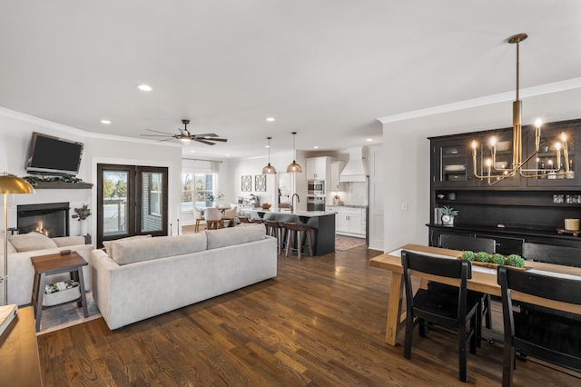 living room featuring dark hardwood / wood-style flooring, sink, ornamental molding, and ceiling fan