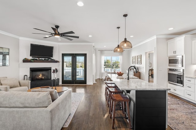 kitchen featuring pendant lighting, light stone counters, white cabinets, and appliances with stainless steel finishes