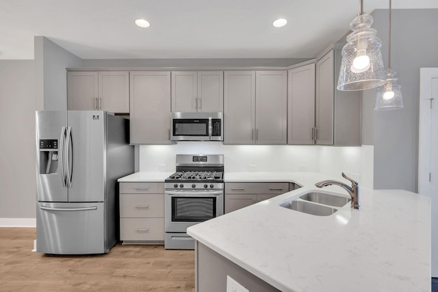 kitchen with sink, gray cabinetry, light wood-type flooring, appliances with stainless steel finishes, and pendant lighting