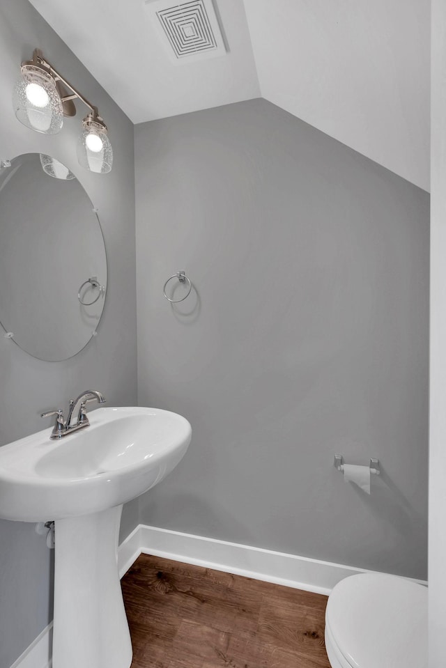 bathroom featuring wood-type flooring, lofted ceiling, and toilet