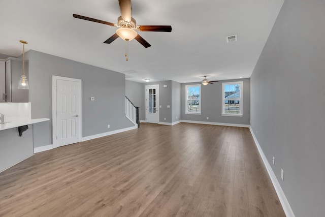 unfurnished living room with ceiling fan, sink, and light hardwood / wood-style flooring