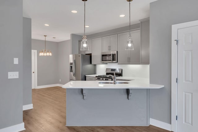 kitchen with pendant lighting, a breakfast bar, kitchen peninsula, and appliances with stainless steel finishes