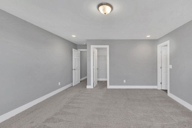 unfurnished bedroom featuring a walk in closet and light colored carpet