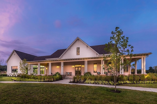 farmhouse-style home with covered porch and a lawn