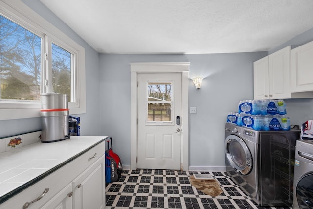 washroom featuring cabinets, washing machine and clothes dryer, and a textured ceiling