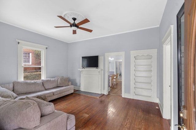 living room featuring dark wood-type flooring, ornamental molding, and ceiling fan