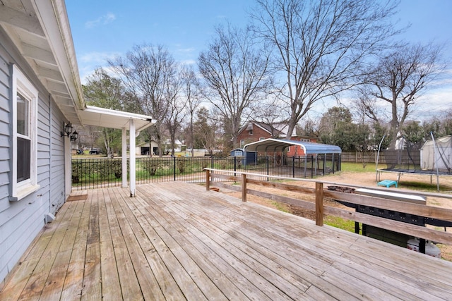 wooden deck with a trampoline and a carport