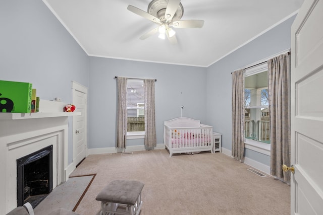 bedroom featuring light carpet, crown molding, a nursery area, and ceiling fan