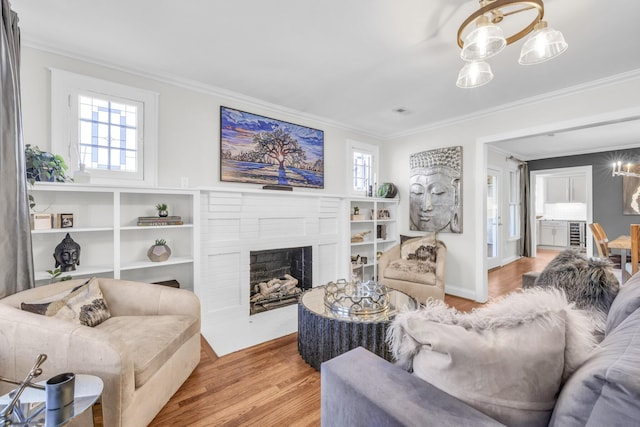 living room featuring ornamental molding, a fireplace, light hardwood / wood-style floors, and a notable chandelier