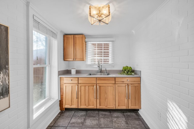 kitchen featuring ornamental molding, brick wall, and sink