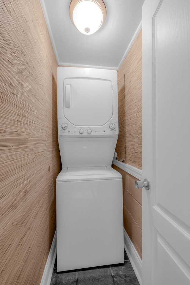 laundry area featuring crown molding and stacked washer / drying machine