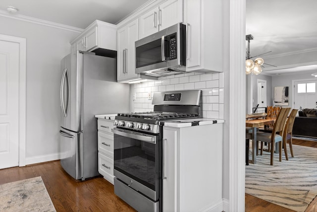 kitchen with dark wood-type flooring, ornamental molding, appliances with stainless steel finishes, and white cabinets