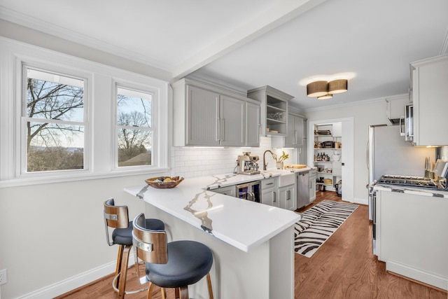 kitchen featuring tasteful backsplash, light hardwood / wood-style flooring, kitchen peninsula, and a kitchen bar