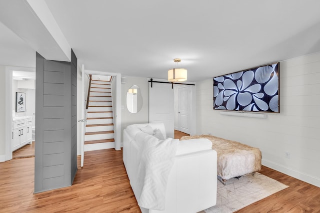 living room with a barn door and light wood-type flooring