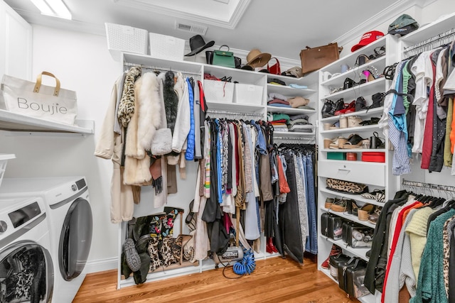 spacious closet with light hardwood / wood-style floors and independent washer and dryer