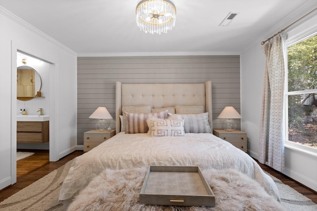 bedroom featuring dark wood-type flooring, crown molding, and a notable chandelier