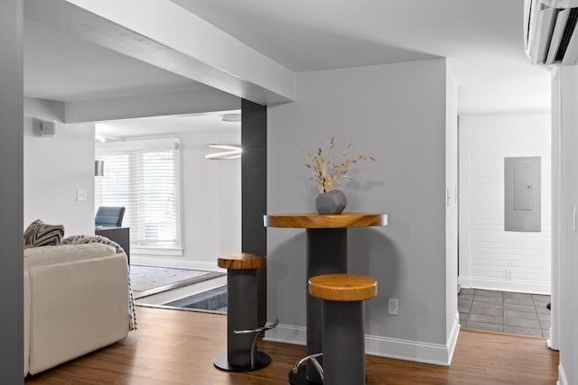 dining room with hardwood / wood-style flooring, brick wall, and electric panel