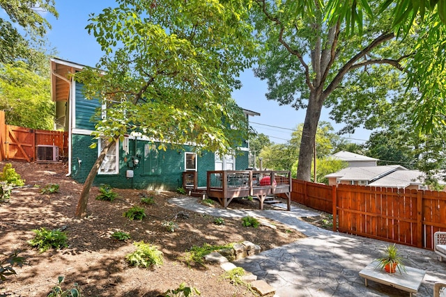 view of yard with a wooden deck, central AC unit, and a patio