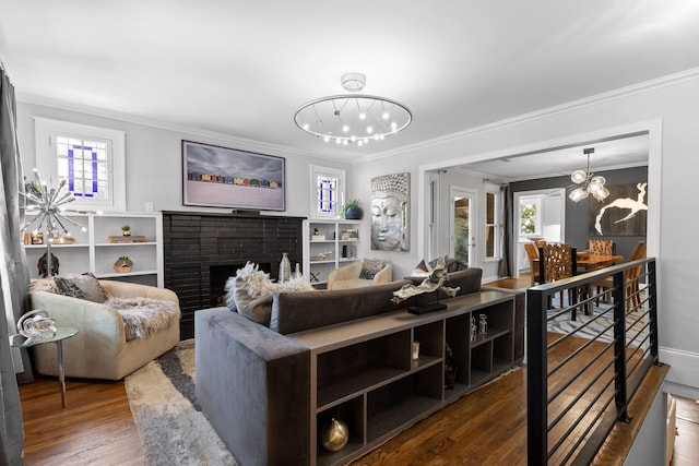 living room featuring a fireplace, wood-type flooring, a chandelier, and a healthy amount of sunlight