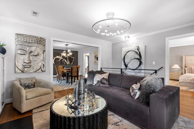 living room featuring hardwood / wood-style flooring, crown molding, and an inviting chandelier