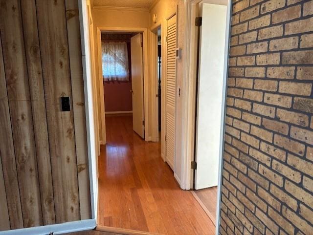 hallway with ornamental molding, brick wall, and hardwood / wood-style floors