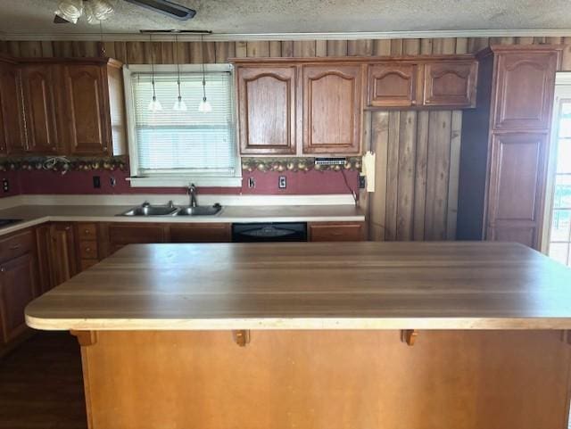 kitchen featuring sink, dishwasher, a center island, and a textured ceiling