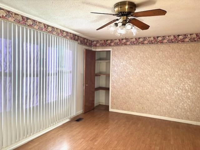 unfurnished room with ceiling fan, hardwood / wood-style floors, and a textured ceiling