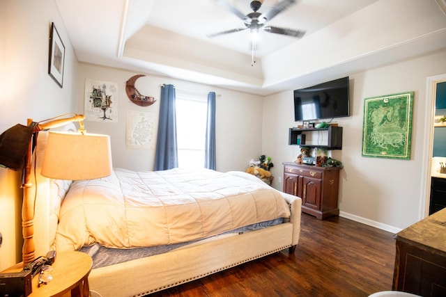 bedroom featuring a raised ceiling, dark hardwood / wood-style floors, and ensuite bath