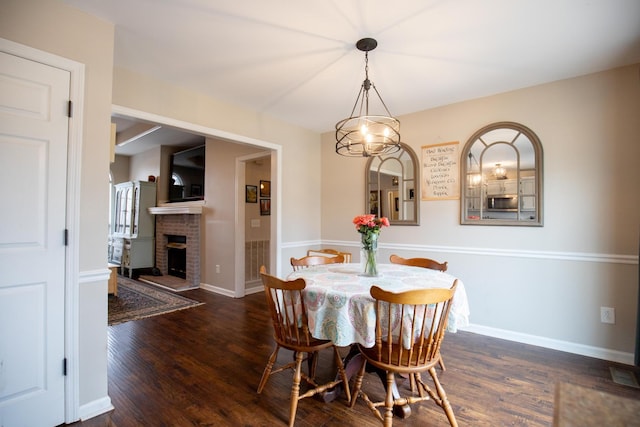 dining area featuring a brick fireplace and dark hardwood / wood-style floors