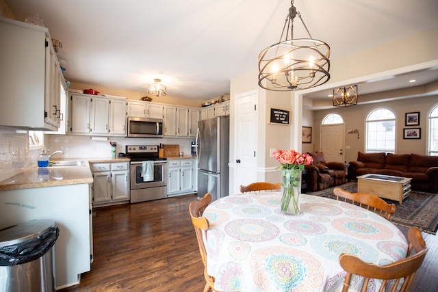 dining room with dark wood-type flooring, a chandelier, and sink